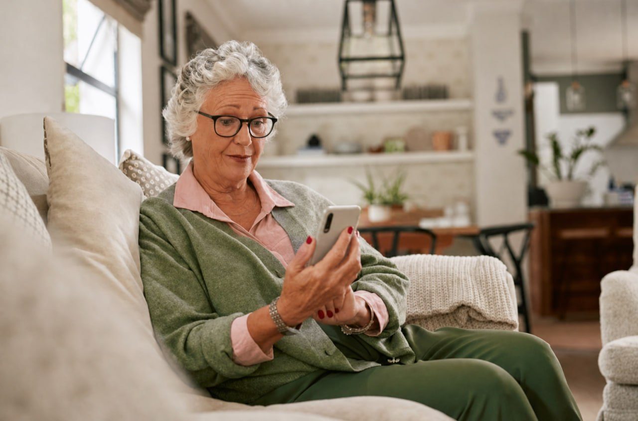 Older woman sitting on a sofa and reading a phone
