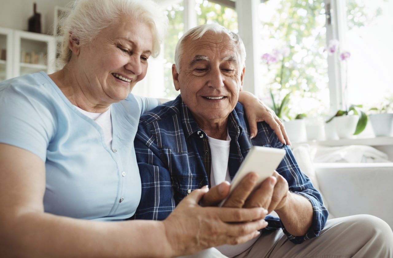 Older couple sitting together and looking at a phone